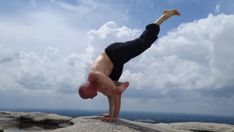 Dr. Sattva in a yoga arm balance on Stone Mountain